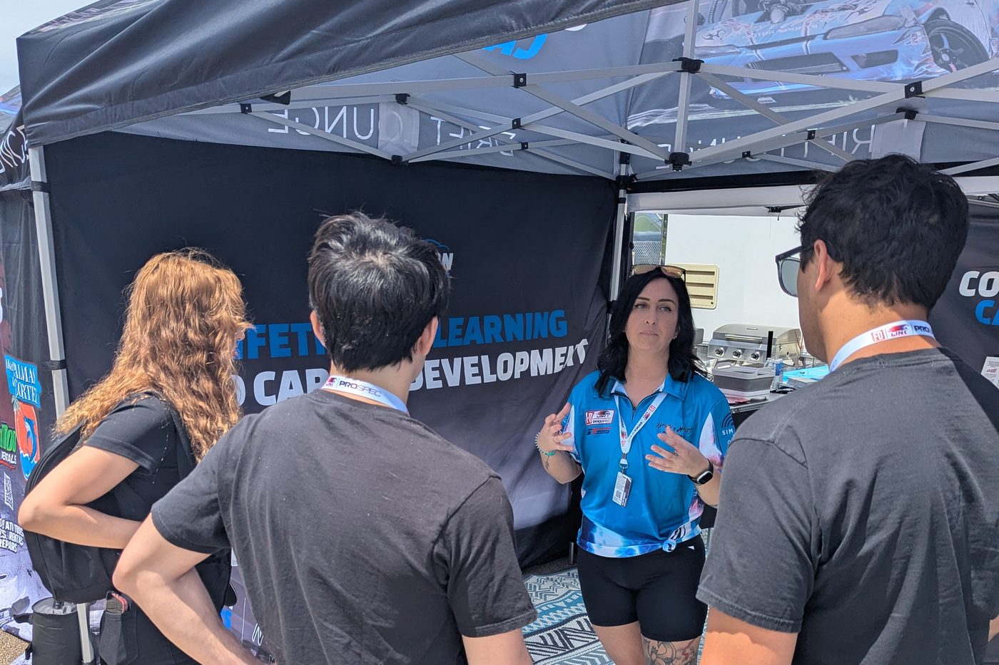 A collision repair educator talking with fans at the trackside Collision Careers footprint