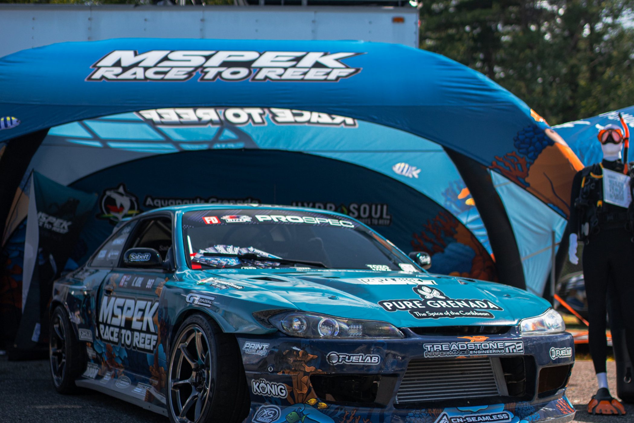 The Race to Reef S15 under the team footprint beside dive gear, partner brands across the livery